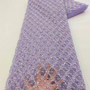 May include: Purple beaded lace fabric with a diamond pattern. The fabric is sheer and has a delicate texture.