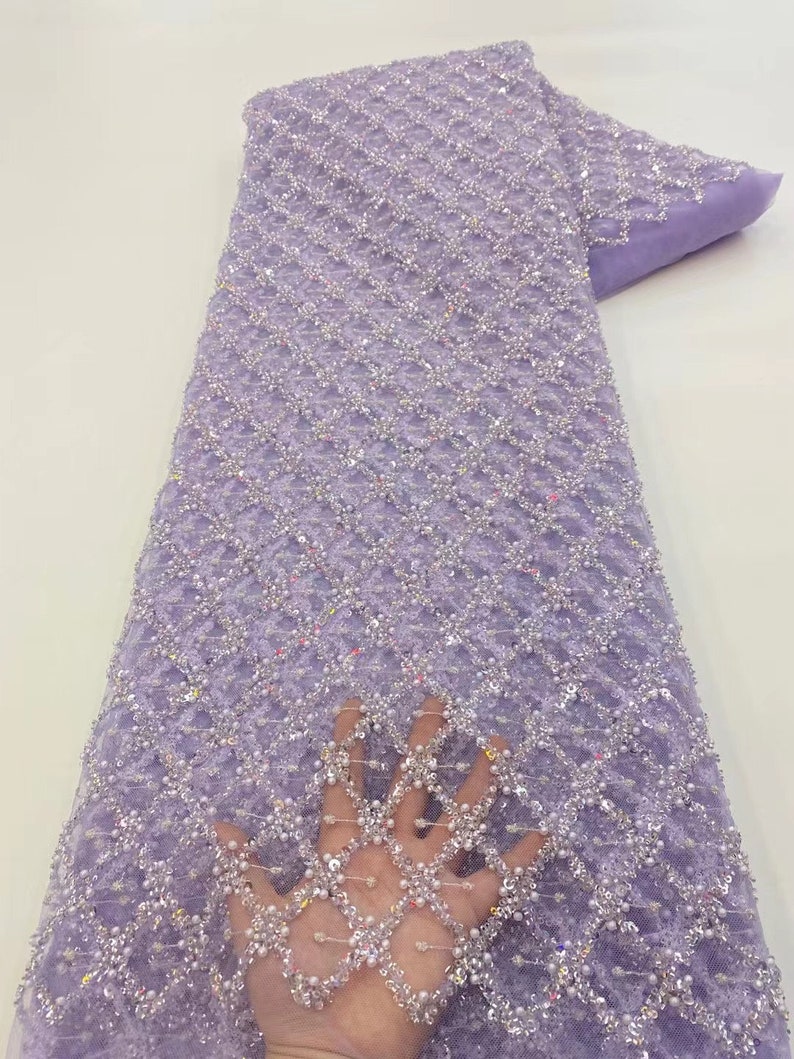 May include: Purple beaded lace fabric with a diamond pattern. The fabric is sheer and has a delicate texture.