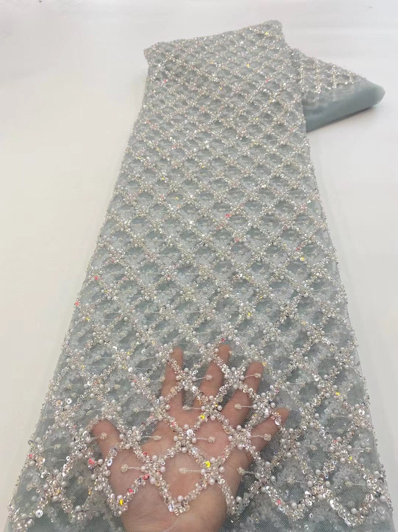 May include: Light blue beaded lace fabric with a diamond pattern. The fabric is embellished with sequins and pearls.