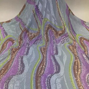 May include: Light blue fabric with a wavy pattern of purple, green, and gold sequins.