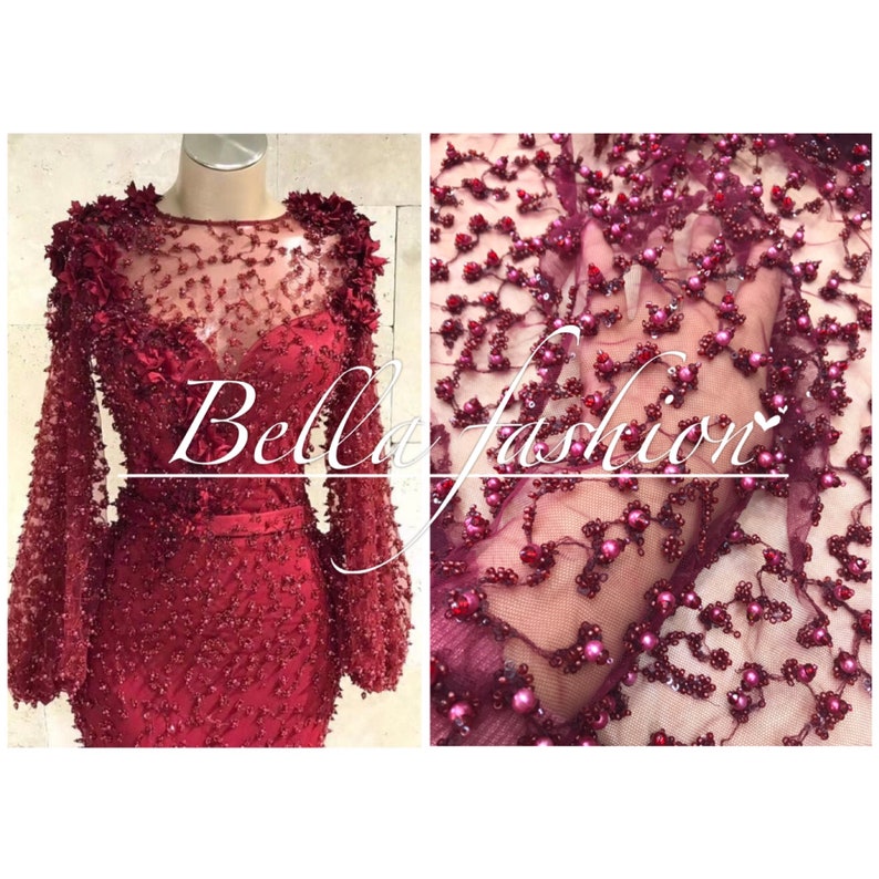 Op de afbeelding: Een bordeauxrode avondjurk met lange mouwen en een doorschijnende halslijn, versierd met ingewikkeld kralenwerk en bloemmotieven. De afbeelding toont ook een close-up van de kralenstof. De tekst "Bella fashion" staat over de afbeelding.
