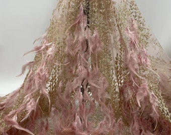 May include: Pink and gold glitter tulle fabric with pink feathers. The fabric has a delicate, sparkly texture and is perfect for adding a touch of glamour to any project.