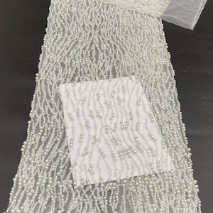 Tessuto in pizzo di tulle con perline, ideale per abiti da sposa e da cerimonia.