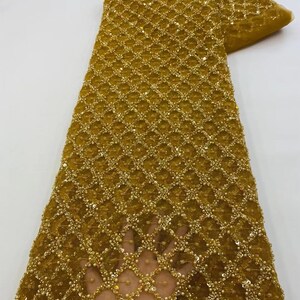 May include: Gold beaded and sequined fabric with a geometric pattern. The fabric is sheer and has a delicate texture.