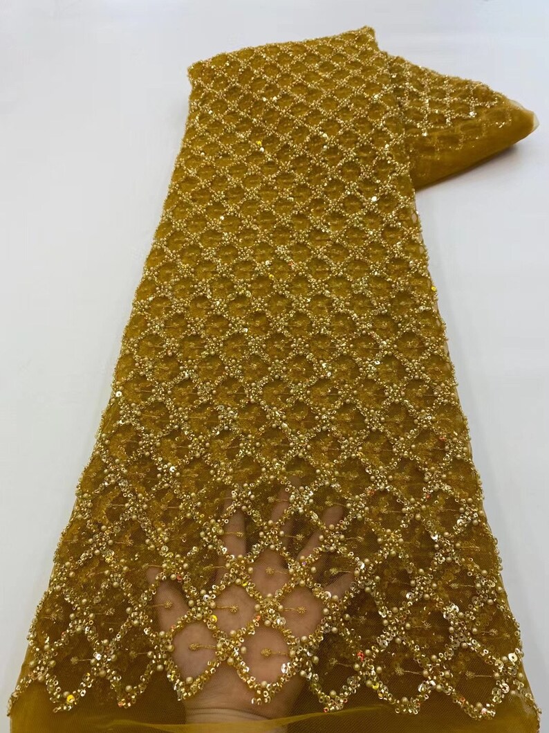 May include: Gold beaded and sequined fabric with a geometric pattern. The fabric is sheer and has a delicate texture.