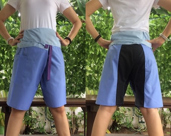 Pode incluir: Uma pessoa vestindo uma camisa branca e shorts azuis com um painel preto nas costas. Os shorts têm uma cintura azul claro e uma gravata roxa.