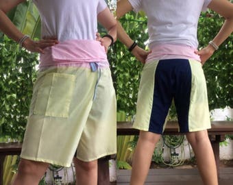May include: A yellow, pink, and blue wrap skirt with a pocket on the front. The skirt is made of a lightweight fabric and has a tie closure at the waist.