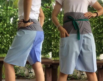 Pode incluir: Duas pessoas vestindo um par de calções de envolver azul, cinza e verde com uma faixa verde. Os calções são feitos de um tecido macio e confortável e têm um ajuste relaxado.