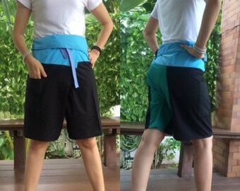 Pode incluir: Duas pessoas vestindo shorts pretos, azuis e verdes com uma faixa azul. Os shorts têm um design único com um painel preto no meio e painéis azuis e verdes nas laterais.