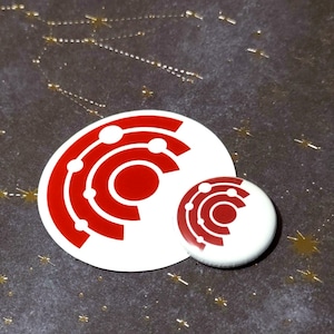 May include: Two white and red circular stickers with a geometric design. The larger sticker is approximately 7.6 cm in diameter, and the smaller one is about 2.5 cm. The stickers have a red design on a white background.