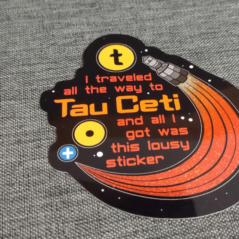 Puede incluir: Pegatina negra con detalles naranjas y blancos, con un cohete y el texto "I traveled all the way to Tau Ceti and all I got was this lousy sticker."