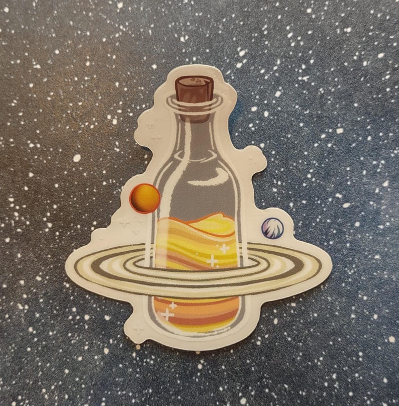 May include: A sticker featuring a clear bottle with a cork, filled with layers of yellow and orange liquid. The bottle is surrounded by a planet with rings and two smaller planets, all set against a starry background.