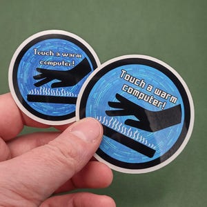 以下が含まれることがあります： 青い背景に「Touch a warm computer！」の文字が入った丸いステッカーが2枚。黒い手と波線の下にある黒い長方形が描かれています。ステッカーは人が持っています。