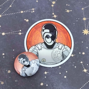 May include: A sticker and a button featuring a futuristic character design. The character has a black and white helmet and a white and grey armoured suit. The sticker is circular with a red and orange background. The button is also circular with a copper-coloured background.