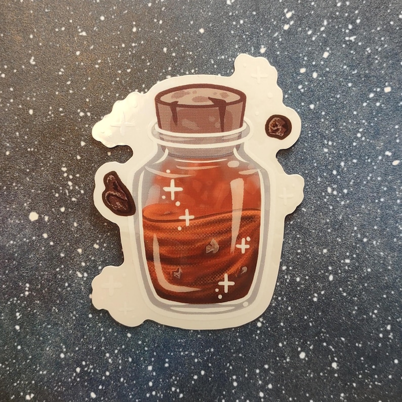 May include: A sticker featuring a cartoon illustration of a potion bottle. The bottle is filled with a reddish-brown liquid and has a brown cork. White cross-shaped sparkles and brown floating objects are also visible.