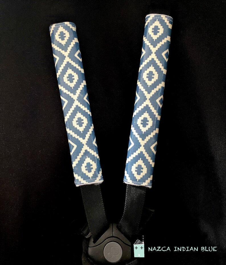 May include: Two blue and white patterned stroller strap covers with the text "NAZCA INDIAN BLUE" on a black background.