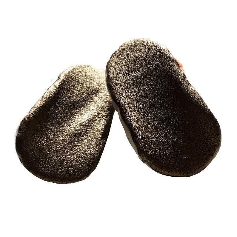 May include: A pair of gold leather baby shoes. The shoes are soft and flexible, perfect for little feet.