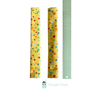 May include: Two yellow fabric covered handles with a multi-colored star pattern. The handles are approximately 12 inches long.  The text "YELLOW STARS" is printed below the handles.