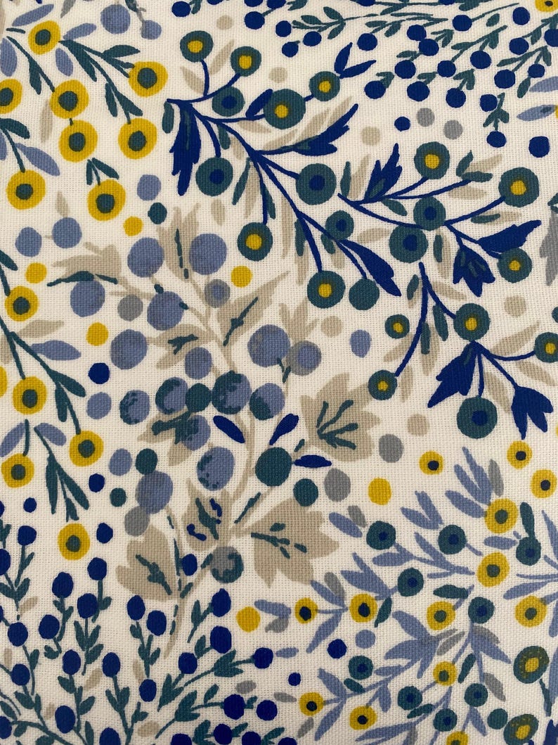 K&ouml;nnte beinhalten: Ein Stoffmuster mit wei&szlig;em Hintergrund und einem dichten botanischen Druck aus kleinen gelben Blumen, hellblauen Beeren, dunkelblauen Beeren und ged&auml;mpften graugr&uuml;nen Bl&auml;ttern, die in einem sich wiederholenden, floralen Design angeordnet sind.