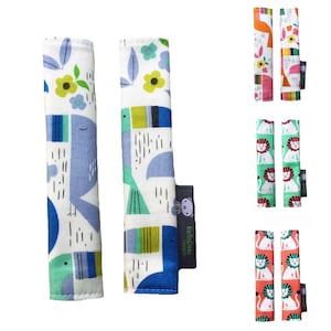 May include: Two pairs of colorful fabric stroller straps with different animal and floral designs. The straps are made by BelloCici Designs.