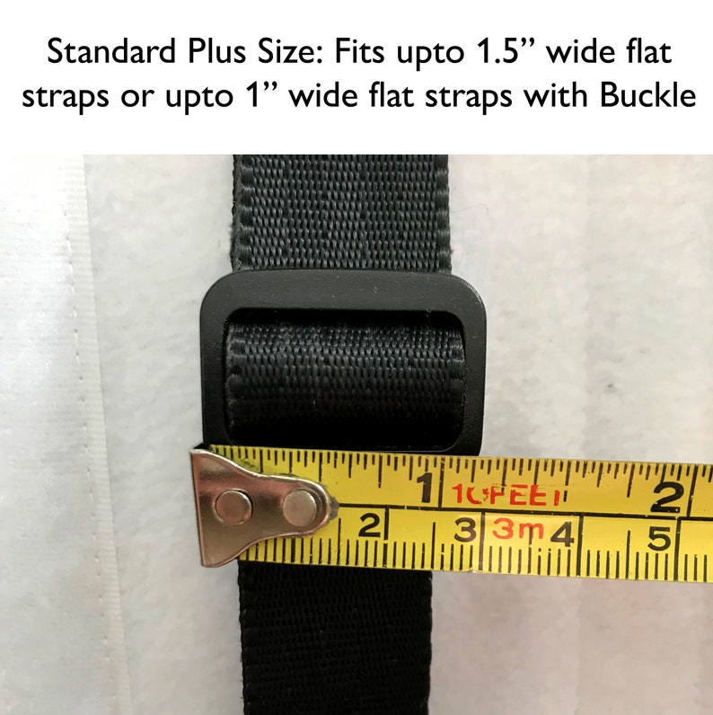 May include: Close-up of a black strap with a black buckle. A yellow measuring tape is placed over the strap, showing that it is 1 inch wide. The text "Standard Plus Size: Fits upto 1.5" wide flat straps or upto 1" wide flat straps with Buckle" is visible at the top of the image.