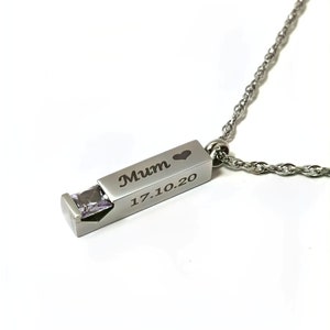 May include: Silver necklace with a rectangular pendant that has a small clear gemstone and the words "Mum" and "17.10.20" engraved on it.