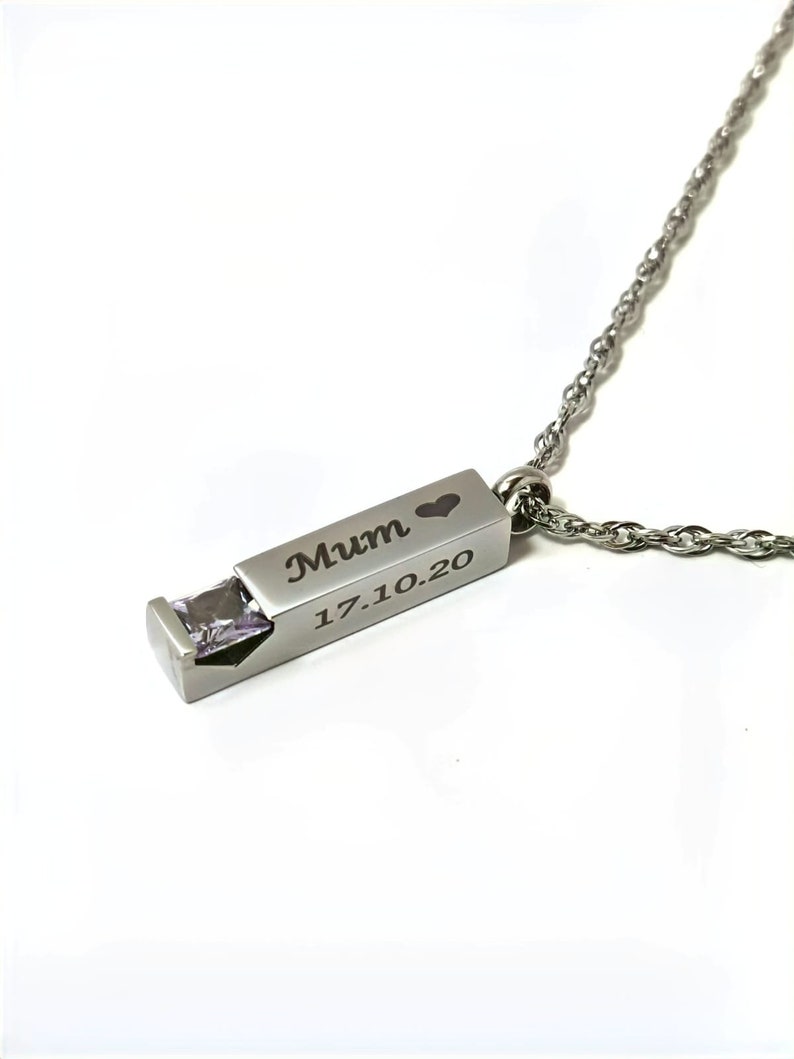 May include: Silver necklace with a rectangular pendant that has a small clear gemstone and the words "Mum" and "17.10.20" engraved on it.