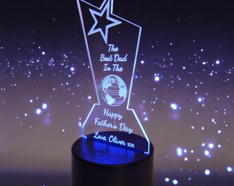 May include: A clear acrylic trophy with a star and a globe design. The trophy has an inscription that reads "The Best Dad In The World" and "Happy Father's Day". The base of the trophy is black and has a blue LED light.
