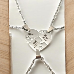 Può includere: Tre collane d'argento con ciondoli a forma di cuore che si incastrano come un puzzle. I ciondoli sono incisi con le parole "Mamma", "Sorella maggiore" e "Sorella minore".