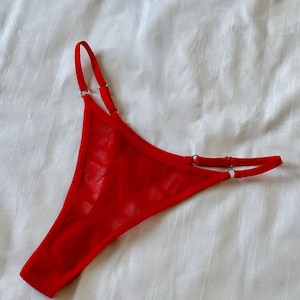 May include: Red mesh lingerie with adjustable straps and silver rings.