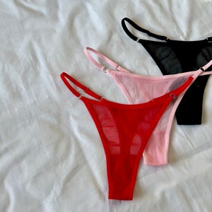 May include: Three pairs of sheer lingerie in red, pink, and black. The lingerie is made of a delicate mesh fabric and has a simple, elegant design.