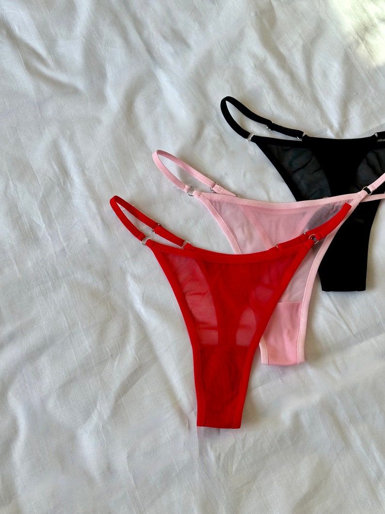 May include: Three pairs of sheer lingerie in red, pink, and black. The lingerie is made of a delicate mesh fabric and has a simple, elegant design.