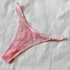 May include: Pink sheer lingerie with delicate straps and a satin trim.