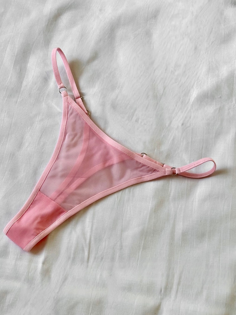 May include: Pink sheer lingerie with delicate straps and a satin trim.