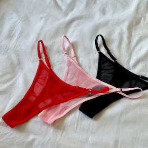 May include: Three pairs of sheer lingerie in red, pink, and black. The lingerie is made of a delicate mesh fabric and has adjustable straps.