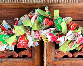 May include: A festive Christmas garland made of fabric scraps in red, green, white, and pink. The garland is draped over a wooden cabinet with intricate carvings.
