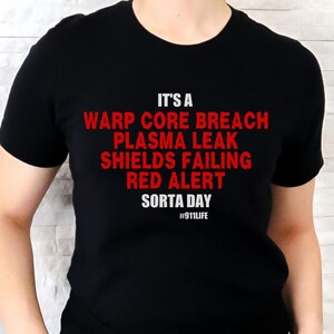 May include: Black t-shirt with white text that reads "It's a Warp Core Breach Plasma Leak Shields Failing Red Alert Sorta Day #911LIFE"