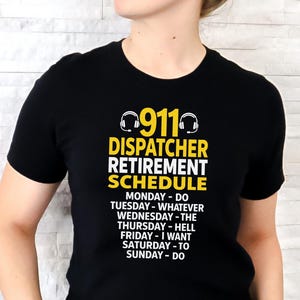 May include: Black t-shirt with the text "911 DISPATCHER RETIREMENT SCHEDULE" in white and yellow. The schedule lists daily activities, including "DO," "WHATEVER," and "HELL." The shirt features a headset graphic above the text.