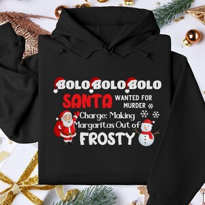 May include: Black hooded sweatshirt with a humorous Christmas design. The graphic includes the text "BOLO SANTA WANTED FOR MURDER" and "Charge: Making Margaritas Out of FROSTY" with Santa and snowman illustrations.