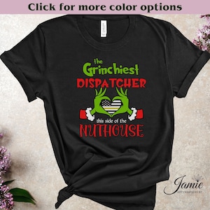 May include: Black t-shirt with a green Grinch-like hand holding a heart with a thin yellow line flag. The text reads "the Grinchiest DISPATCHER this side of the NUTHOUSE".
