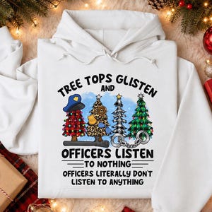 May include: A white hooded sweatshirt featuring a graphic of four Christmas trees with police-themed elements, including a blue police cap, a badge, and handcuffs. The text reads: TREE TOPS GLISTEN AND OFFICERS LISTEN TO NOTHING OFFICERS LITERALLY DON'T LISTEN TO ANYTHING.