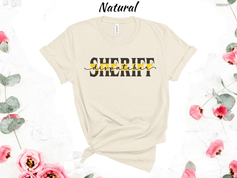May include: A beige t-shirt with a black graphic that says "SHERIFF dispatcher" with a yellow stripe above the text.
