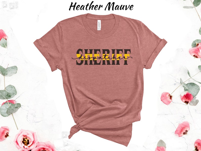 May include: Heather mauve t-shirt with black text that reads "SHERIFF dispatcher" with a yellow and black stripe across the text.