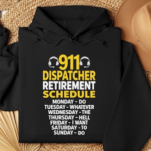 May include: Black hoodie with the text "911 Dispatcher Retirement Schedule" in yellow and white. The text includes the days of the week and the activities associated with each day. The hoodie also features a graphic of a headset.