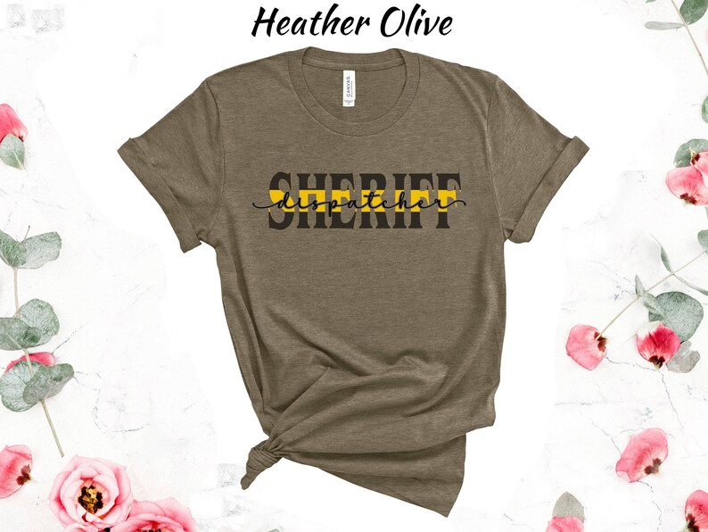 May include: A heather olive t-shirt with the text "SHERIFF dispatcher" in black lettering with a yellow stripe across the text.