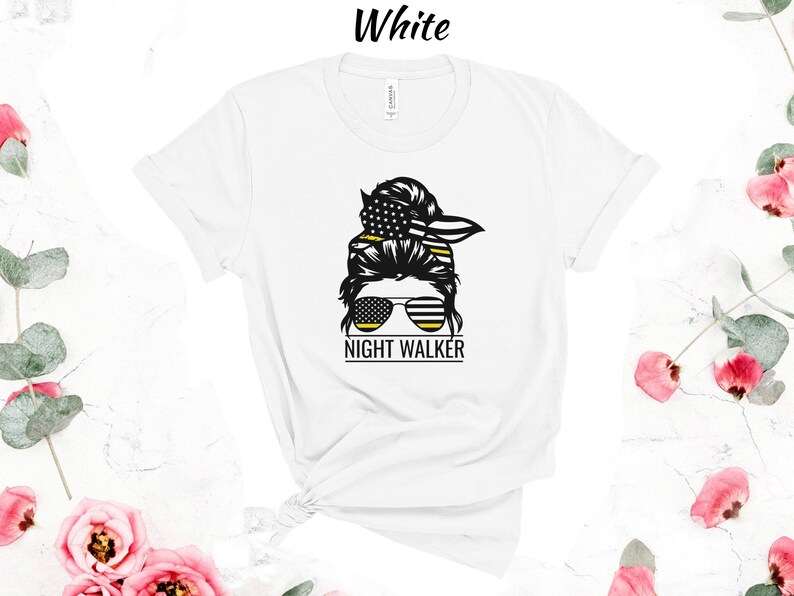 May include: White t-shirt featuring a black and yellow graphic of a woman with a messy bun, sunglasses, and the text "NIGHT WALKER".