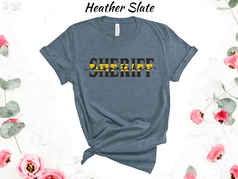 May include: Heather slate blue t-shirt with a black graphic that says "SHERIFF dispatcher" with a yellow stripe across the top of the text.