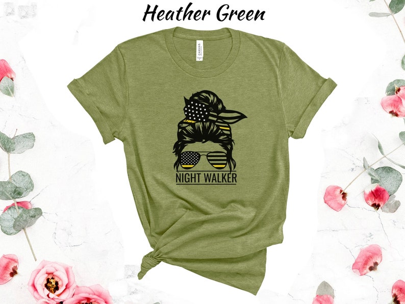 May include: A green t-shirt featuring a graphic of a woman's hair in a bun with an American flag bandana and sunglasses. The text "Night Walker" is below the graphic.