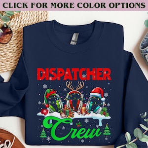 May include: Navy blue sweatshirt with the word "DISPATCHER" in red, above three decorated headsets. The word "Crew" is in green script below. The headsets are decorated with Christmas themes.