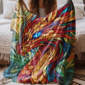 May include: A colourful throw blanket featuring a stained glass style dragon with a blue eye. The blanket is made of soft, plush fabric and is perfect for adding a touch of whimsy to any room.